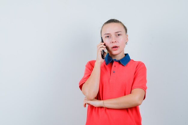 Bezpłatne zdjęcie młoda dama rozmawia przez telefon komórkowy w koszulce i wygląda zamyślony