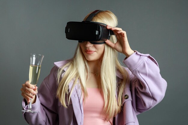 Młoda dama trzyma kieliszek szampana i nosi okulary VR