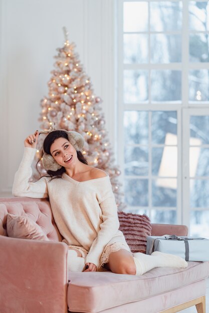 Młoda dama w białej sukni na kanapie w czasie świąt Bożego Narodzenia