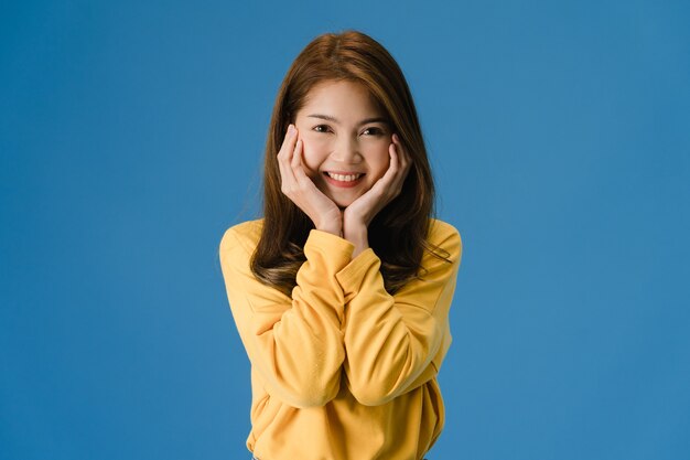 Młoda dama z Azji z pozytywnym wyrazem twarzy, szeroko uśmiechnięta, ubrana w zwykły materiał i patrząc na aparat na niebieskim tle. Szczęśliwa urocza szczęśliwa kobieta raduje się z sukcesu. Koncepcja wyrazu twarzy.