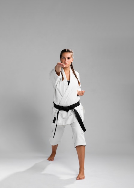 Młoda dorosła kobieta z czarnym pasowym wojownikiem trenuje karate