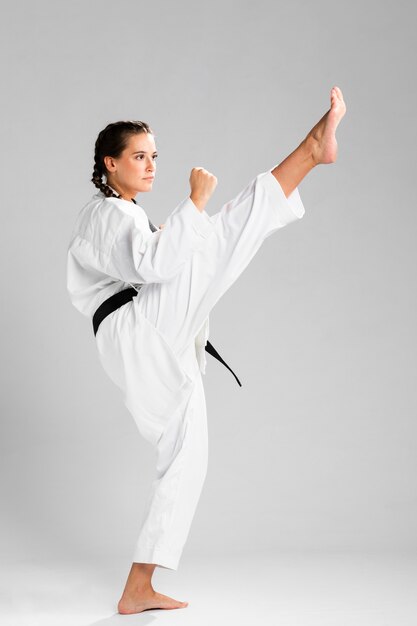 Młoda dorosła kobieta z czarnym pasowym wojownikiem trenuje karate