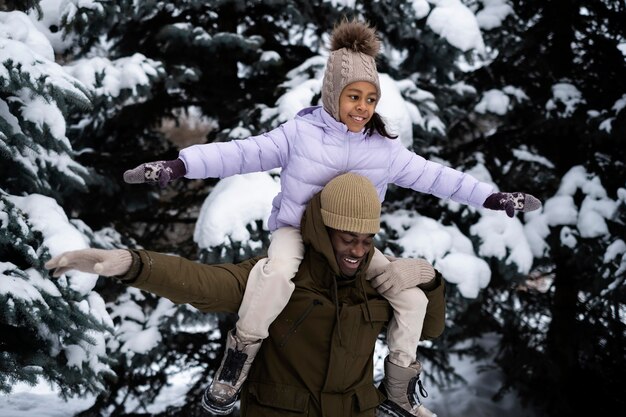 Młoda dziewczyna bawi się z ojcem w śnieżny zimowy dzień