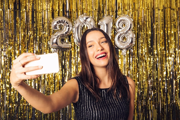 Młoda dziewczyna biorąc selfie na uroczystości nowego roku