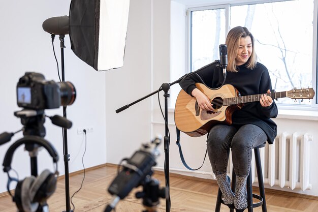 Młoda dziewczyna gra na gitarze, nagrywając wideo i dźwięk