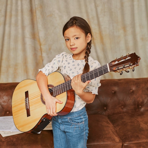 Młoda dziewczyna gra na gitarze w domu