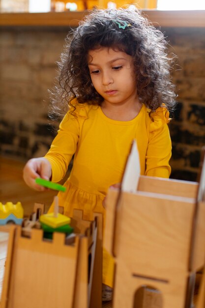 Młoda dziewczyna gra w pomieszczeniu z ekologicznymi zabawkami