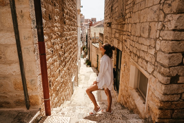Młoda dziewczyna idąc przez starożytne wąskie uliczki w piękny letni dzień