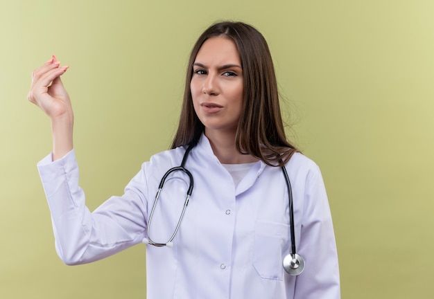 młoda dziewczyna lekarza noszenie stetoskop medycznej sukni pokazując gest środków pieniężnych na zielonej ścianie