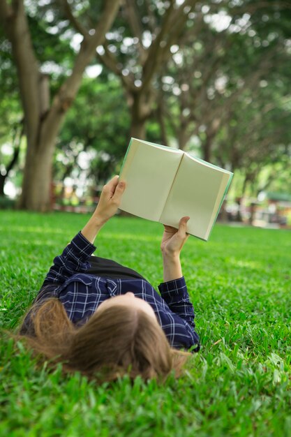 Młoda Dziewczyna Leżącego Na Trawie i Czytanie Książki