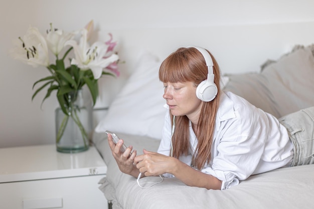 Bezpłatne zdjęcie młoda dziewczyna słucha muzyki w łóżku kwiat lilii w pomieszczeniu