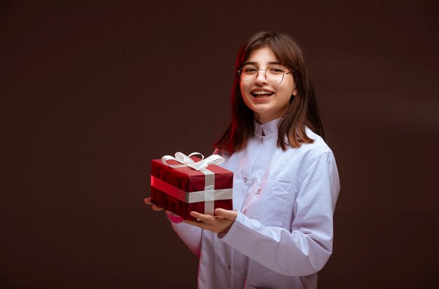 Młoda dziewczyna trzyma czerwone pudełko i patrząc na.