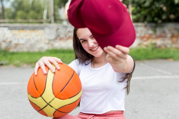 Młoda dziewczyna trzyma koszykówkę i jej czapkę