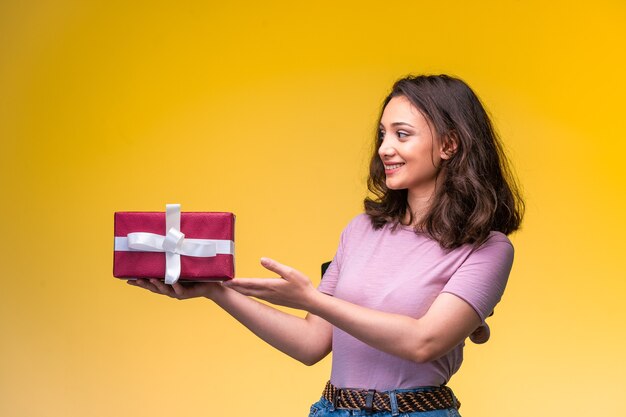Młoda dziewczyna trzyma pudełko na jej rocznicę i wygląda na szczęśliwą