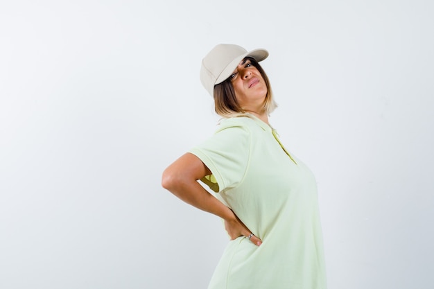 Bezpłatne zdjęcie młoda dziewczyna, trzymając się za ręce za talią w t-shirt i czapkę i patrząc wyczerpany. przedni widok.