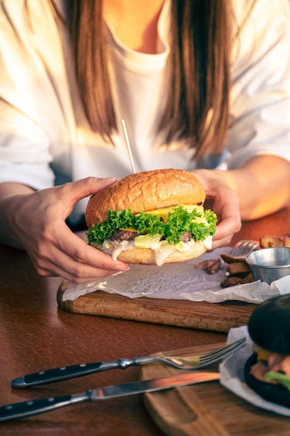 Młoda dziewczyna trzymająca w rękach kobiet burgera fast food z bliska