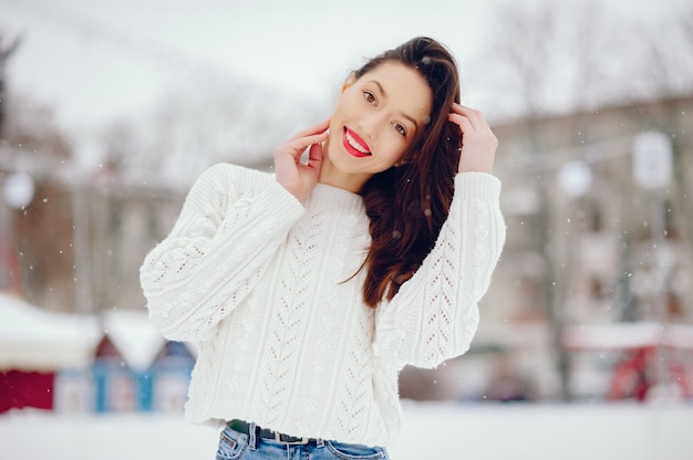 Młoda dziewczyna w białej pulower pozyci w zima parku