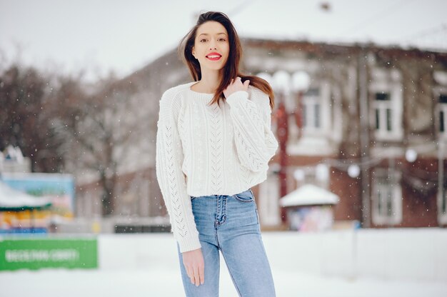 Młoda dziewczyna w białej pulower pozyci w zima parku