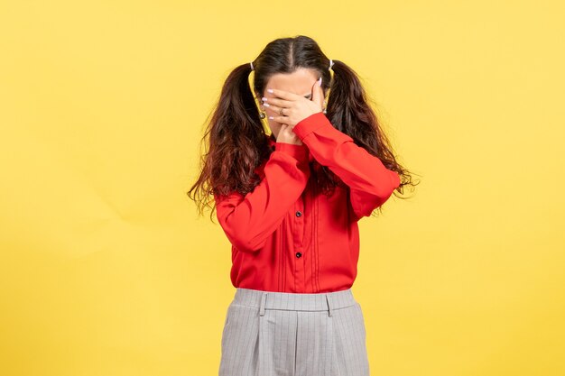 młoda dziewczyna w czerwonej bluzce zakrywającej twarz na żółto