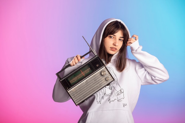 Bezpłatne zdjęcie młoda dziewczyna w strojach sportowych, trzymając vintage radio i słuchanie muzyki.