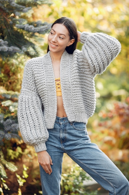 Młoda dziewczyna w szarym swetrze pozuje outdoors