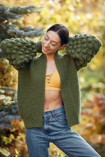 Młoda dziewczyna w zielonym pulowerze pozuje outdoors