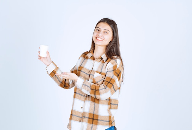 młoda dziewczyna z filiżanką herbaty szczęśliwy na białej ścianie.