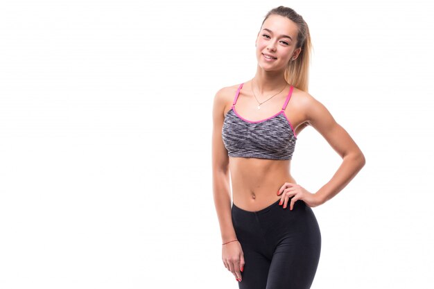 Młoda fitness dziewczyna pokazuje swoje mięśniowe silne ciało na białym