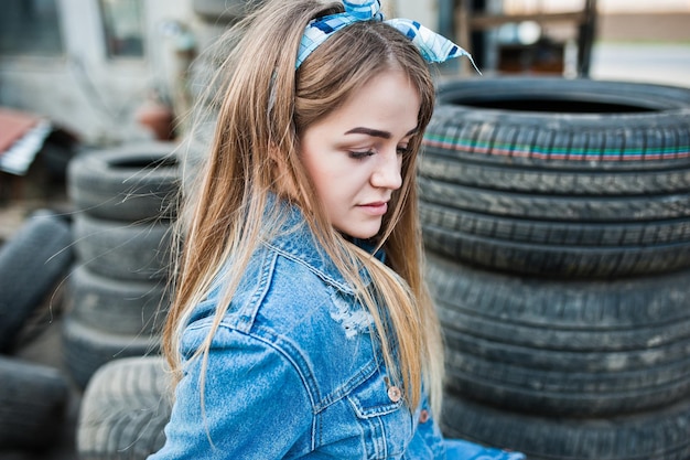 Bezpłatne zdjęcie młoda hipster dziewczyna w jeansowej kurtce i szaliku na głowie w strefie montażu opon