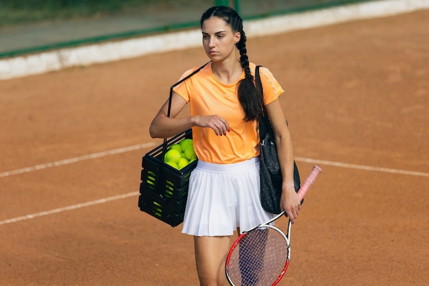 Młoda kaukaska kobieta gra w tenisa na korcie tenisowym na zewnątrz