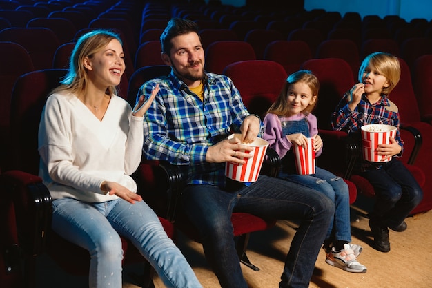 Młoda kaukaska rodzina ogląda film w kinie, domu lub kinie. Wyglądaj wyraziście, zdziwiony i emocjonalny. Siedzenie samotnie i dobra zabawa. Relacja, miłość, rodzina, dzieciństwo, weekend.