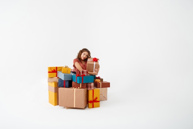 Bezpłatne zdjęcie młoda kędzierzawa kobieta wśród prezentów pudełek