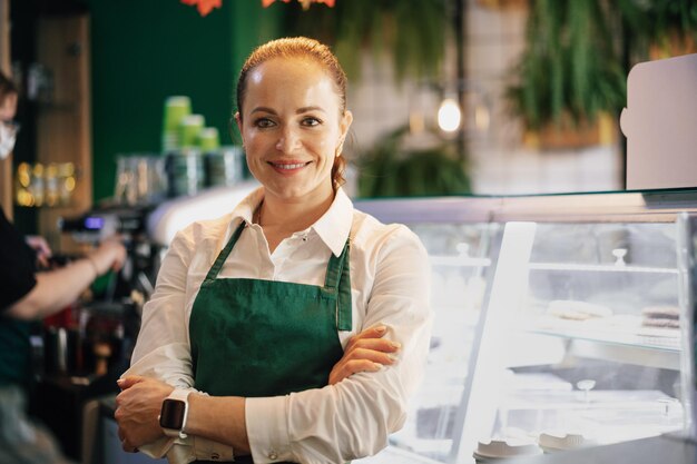 Młoda kobieta baristka stojąca w blacie z kawą