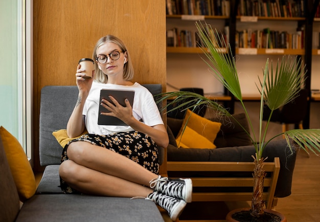 Bezpłatne zdjęcie młoda kobieta cieszy kawę w bibliotece