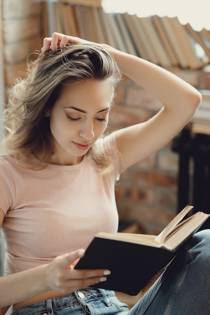 Bezpłatne zdjęcie młoda kobieta czyta książkę w domu