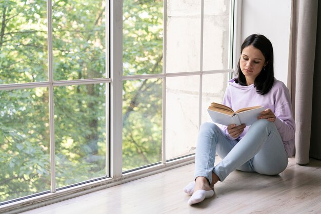 Młoda kobieta czytająca z książki w domu
