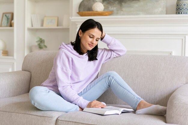 Młoda kobieta czytająca z książki w domu