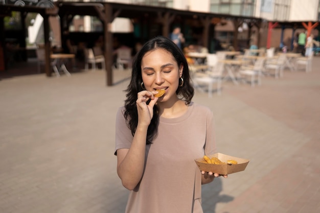 Bezpłatne zdjęcie młoda kobieta delektująca się ulicznym jedzeniem na świeżym powietrzu