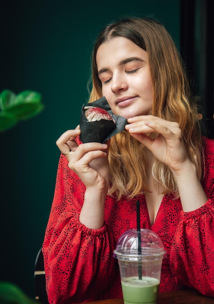 Bezpłatne zdjęcie młoda kobieta delektuje się malinową babeczką w kawiarni