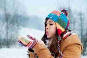 Bezpłatne zdjęcie młoda kobieta dmuchanie śniegu daleko