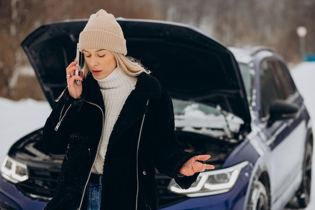 Bezpłatne zdjęcie młoda kobieta dzwoni do telefonu po awarii jej samochodu w sezonie zimowym