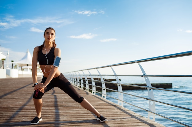 Młoda kobieta fitness, która sprawia, że ćwiczenia sportowe z morzem w tyle