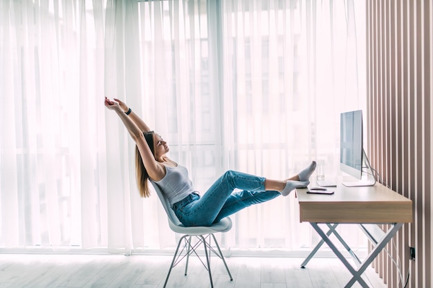 Młoda kobieta freelancer rozciąganie i relaksująca praca na laptopie w domowym biurze