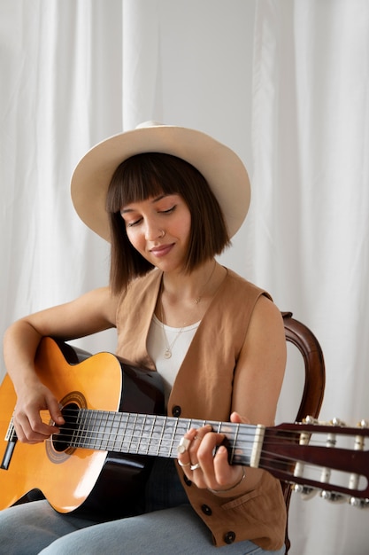 Bezpłatne zdjęcie młoda kobieta gra na gitarze w pomieszczeniu