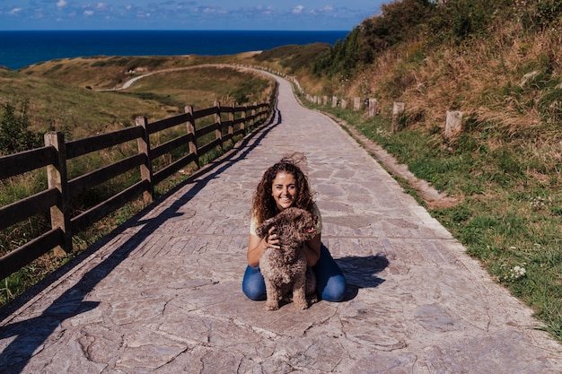 Młoda kobieta i jej śliczny hiszpański wodny pies outdoors cieszy się wpólnie w pogodnym i wietrznym dniu.