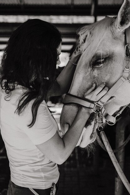 Młoda kobieta i koń, uczucia, troska, czułość, czułość, kobieta przytula i całuje konia. Bliska szczęśliwa młoda kobieta przytula konia.