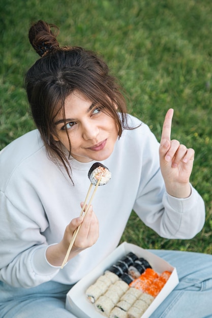 Bezpłatne zdjęcie młoda kobieta je sushi na pikniku w parku w naturze