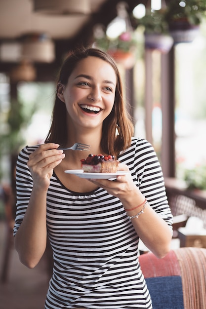 Młoda kobieta je truskawkowego cheesecake