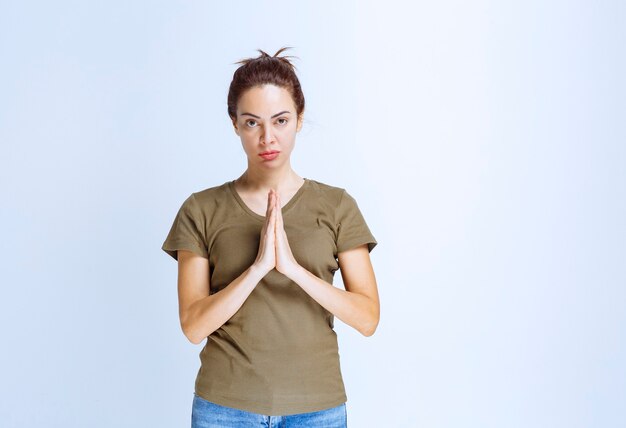 Bezpłatne zdjęcie młoda kobieta łącząca ręce i śniąca lub modląca się