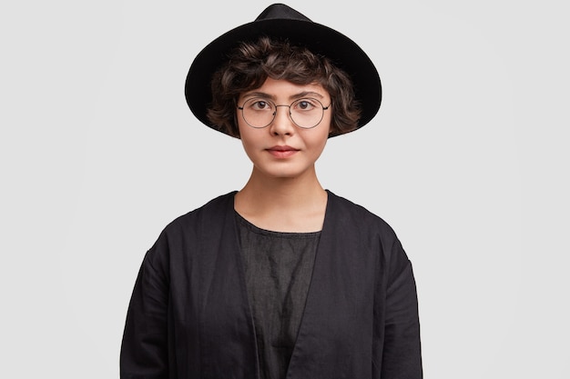 Młoda kobieta ma na sobie wszystkie czarne ubrania i okrągłe okulary